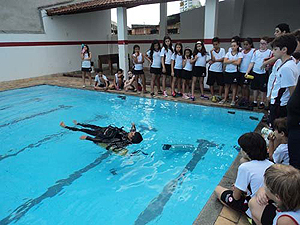 Alunos observam demonstração de flutuação na piscina Alunos observam demonstração de flutuação na piscina